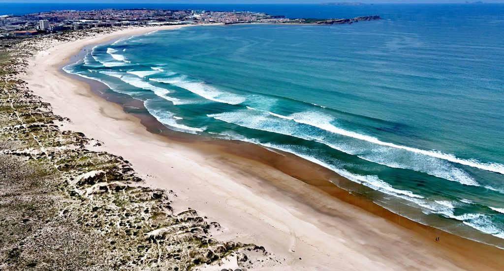 A sheltered sandy beach south of a small headland, with gentle waves and calm water close to shore