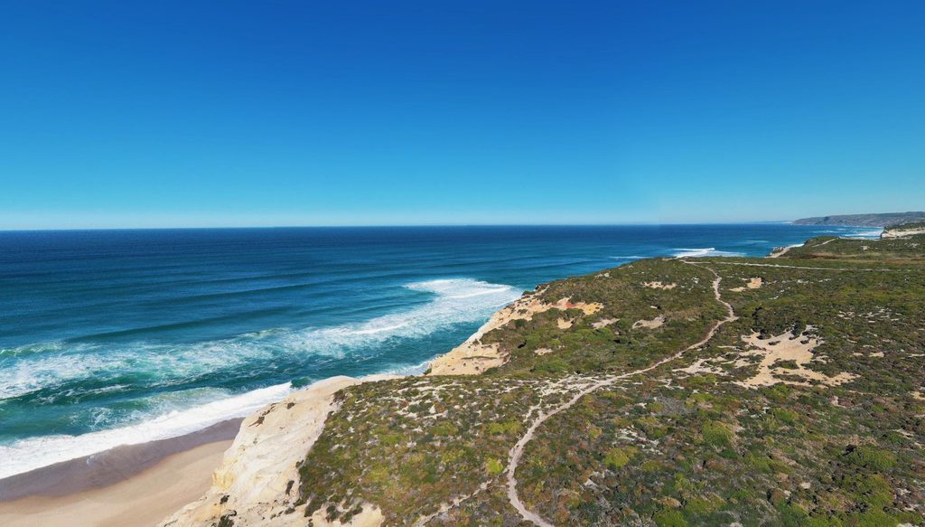 An open, exposed sandy beach with waves breaking along the Óbidos Coast