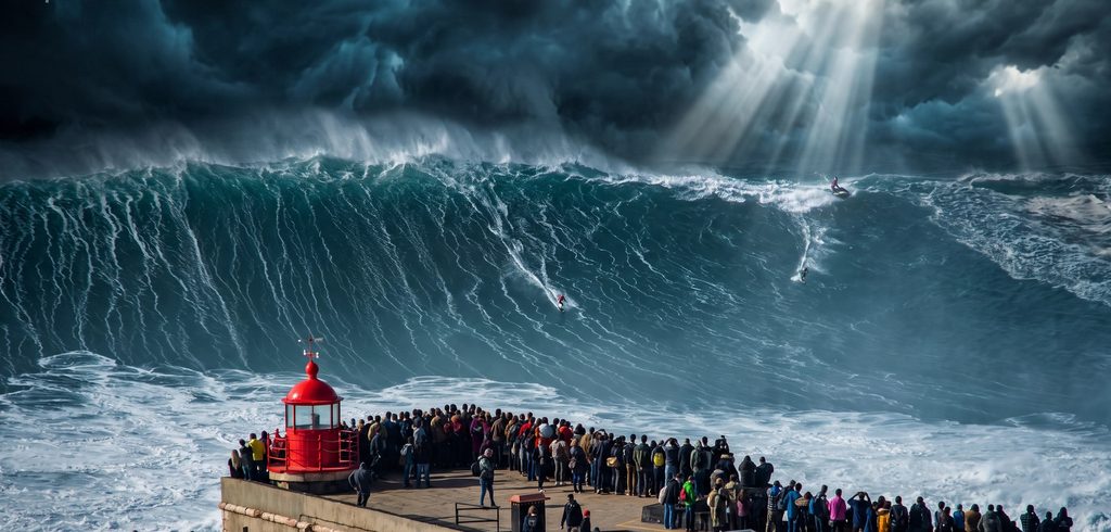 A giant storm-lit wave breaking beside the red lighthouse at Praia do Norte, Nazaré, with tow surfers, a jet-ski and spectators gathered on the pier