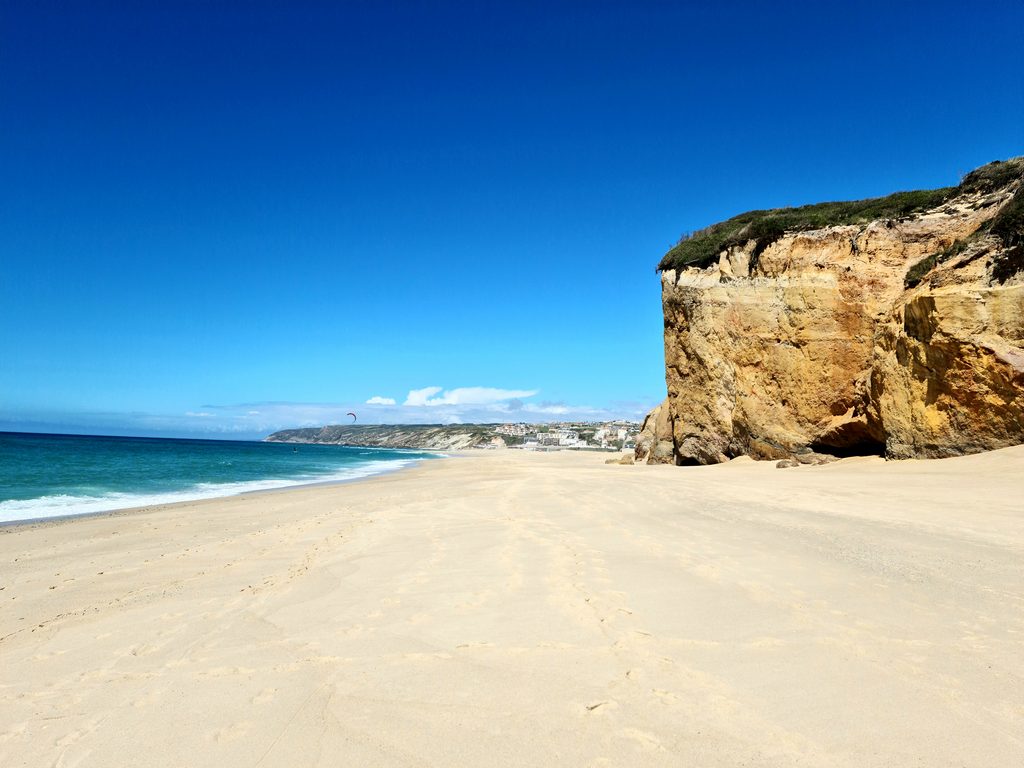 Calm, shallow lagoon water at Bom Sucesso with a wide sandy shore and distant dunes