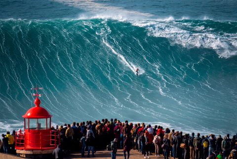 A big-wave surfer riding down the face of a large wave at Praia do Norte