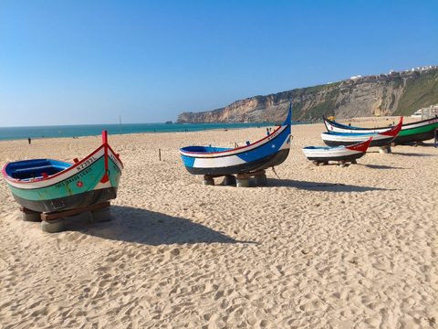 Traditional colourful Nazaré fishing boats resting on the sand