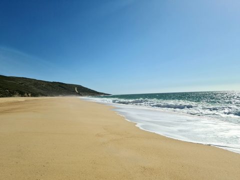 The long, wild stretch of Praia do Salgado south of Nazaré, backed by cliffs
